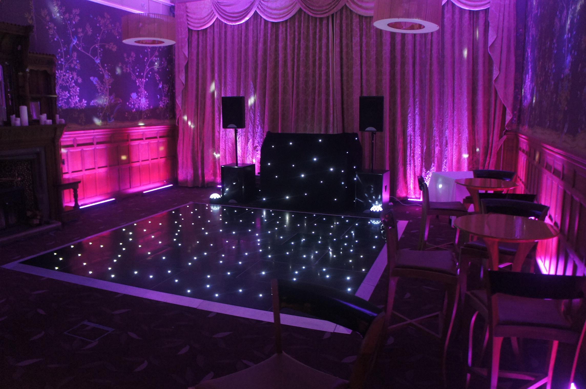 black led dance floor with a DJ setup and pink uplighters