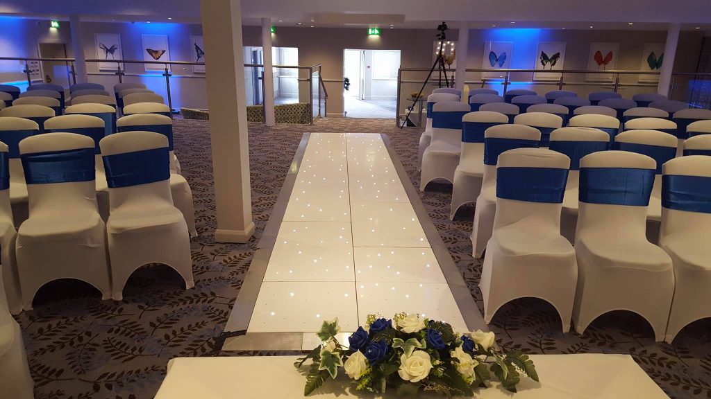 White starlit aisle with chairs with blue sashes either side