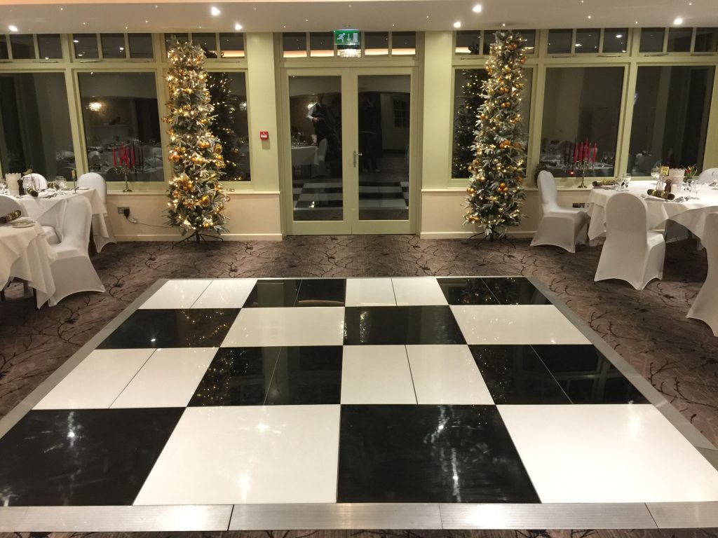 black and white dance floor in the middle of a room with 2 Christmas trees