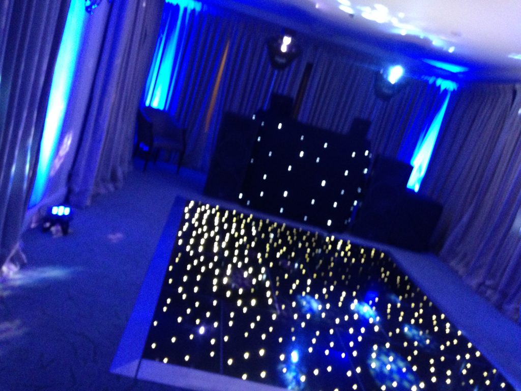 Black twinkle dance floor with blue room lighting and a disco behind