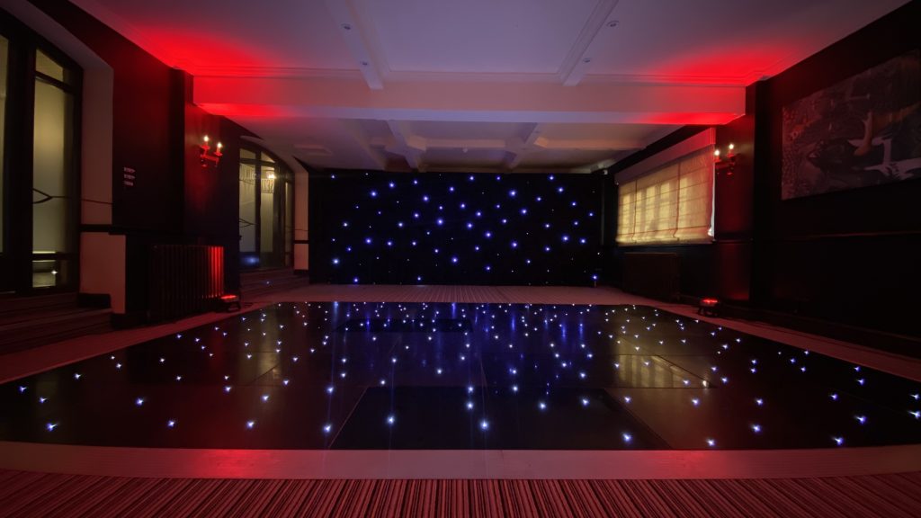 Black dance floor with LEDs and black backdrop with red lighting