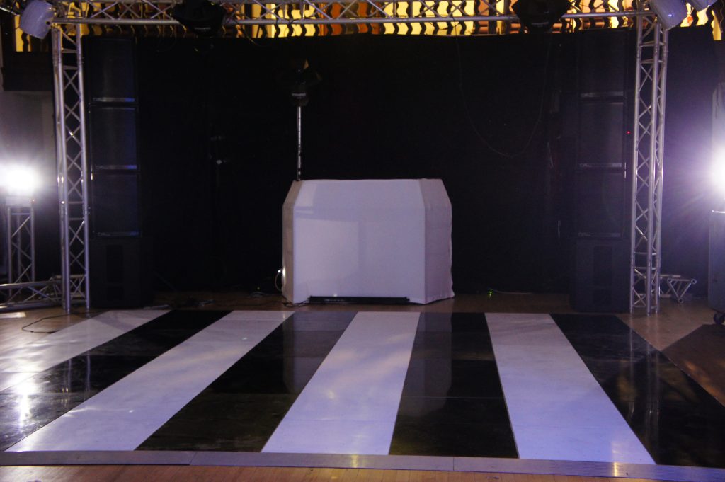 black and white stripped dance floor infront of white DJ booth