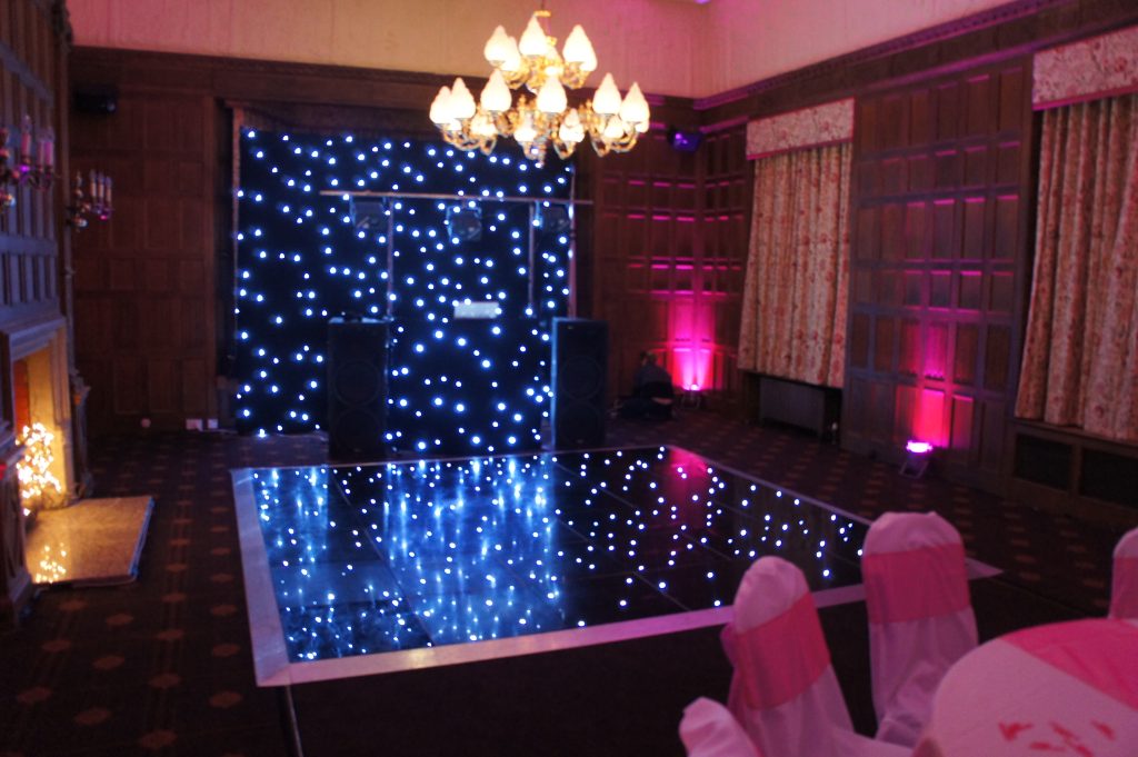 Black starlit dance floor with pink lighting and black starcloth backdrop. 