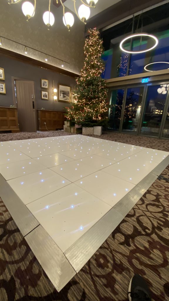 White starlit dance floor with Christmas tree setup behind