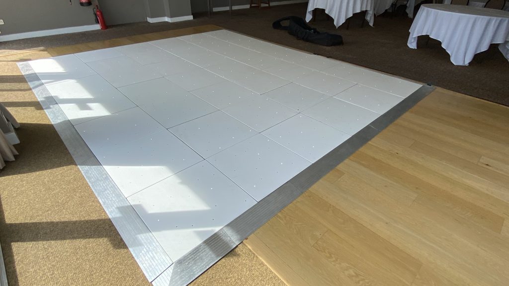 White dance floor installed over a wooden dance floor