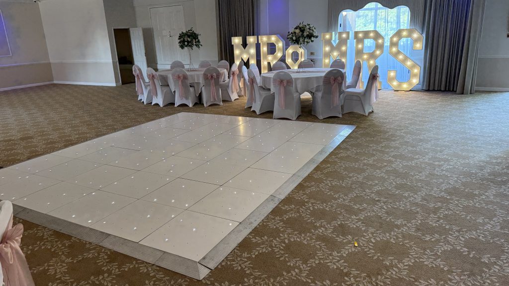 White starlit dance floor with tables and light up letters behind