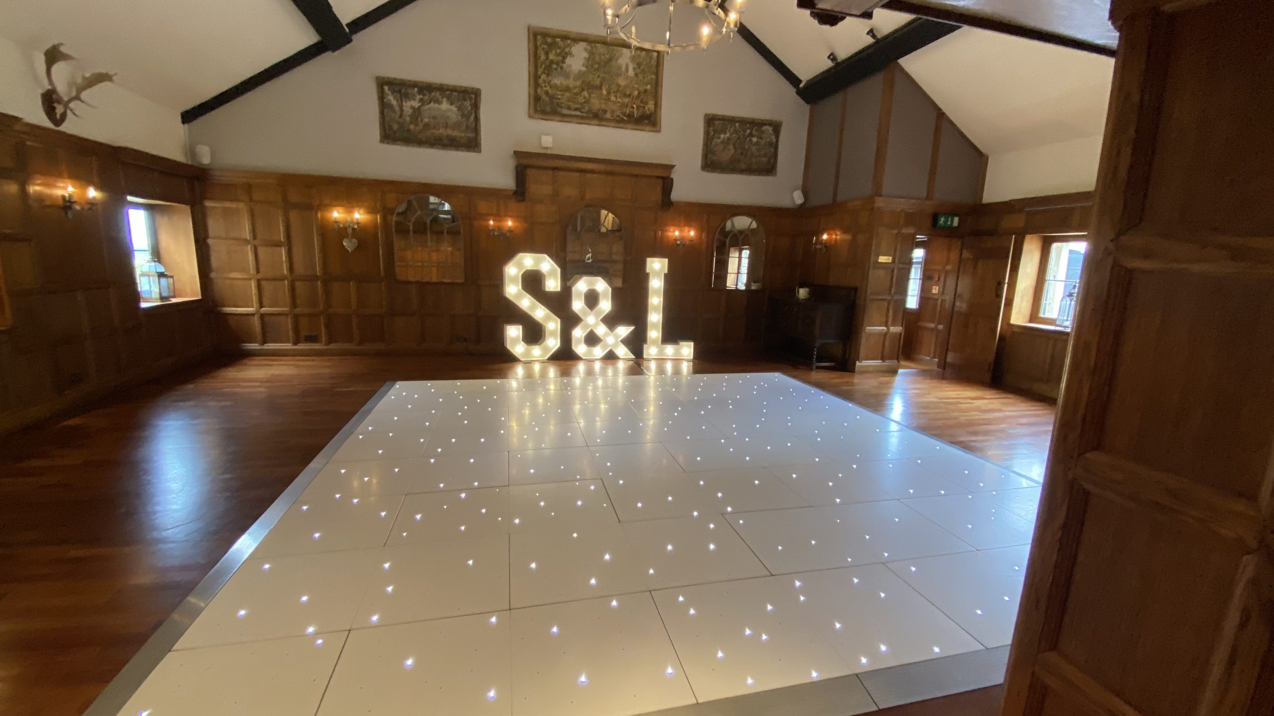 16' x 16' white starlit dance floor with S & L large light up letters behind in a wood panneled room.