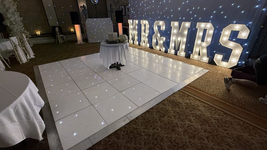 White starlit dance floorwith MR & MR letters behind and a wedding cake on the dance floor