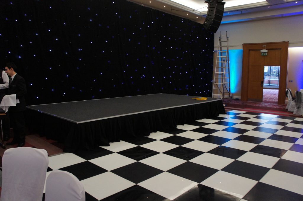 black and white chequered dance floor in front of a stage at a corporate event