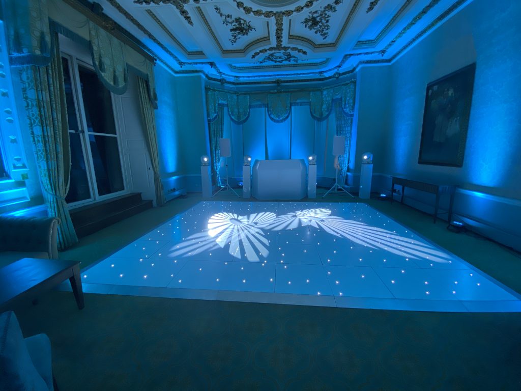 White starlit dance floor with blue lighting and a white disco setup in a ballroom