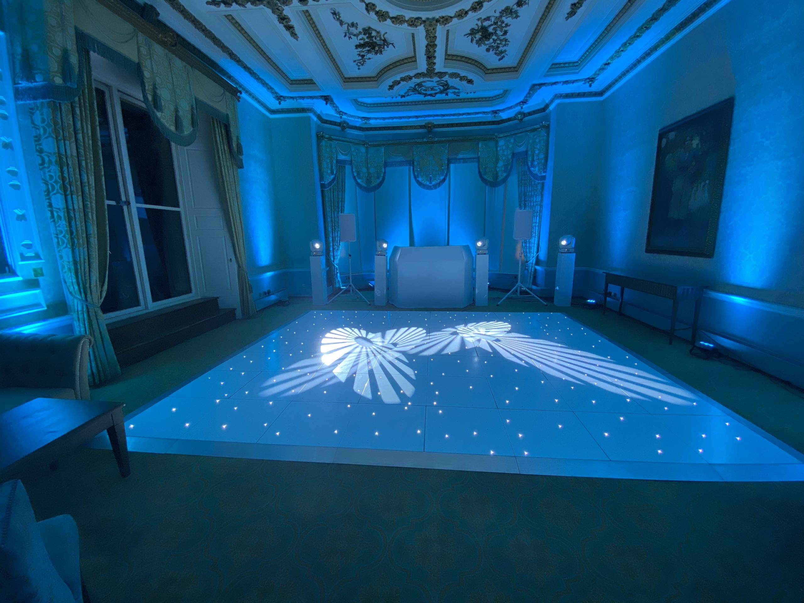 White starlit dance floor with blue lighting and a white disco setup in a ballroom