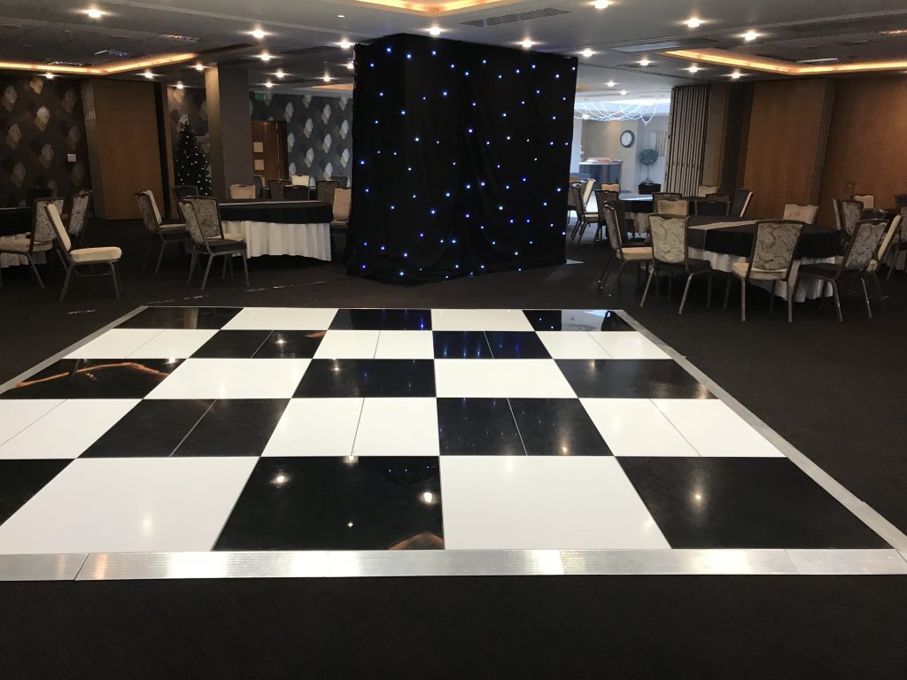 Black and white dance floor setup in hotel function room between tables