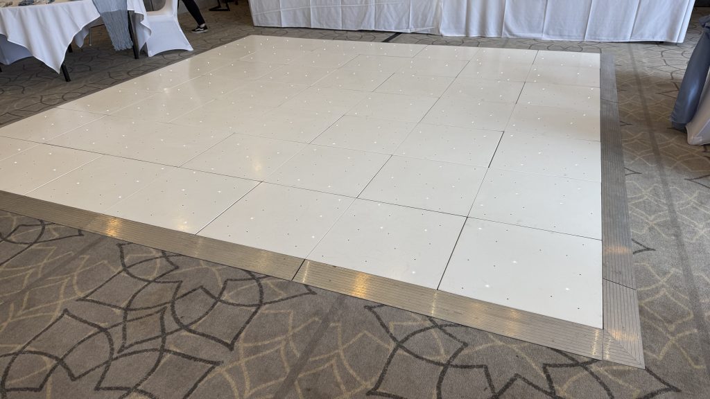 White starlit dance floor in front of a white wedding backdrop