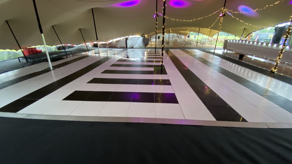 Wide view of the bespoke black and white dance floor fitted around the marquee’s central support poles